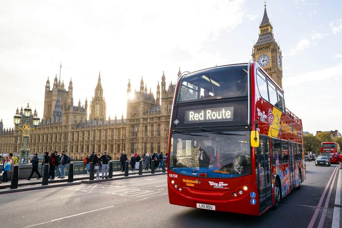 Un bus touristique rouge à impériale dans une rue près des Chambres du Parlement et de Big Ben à Londres.