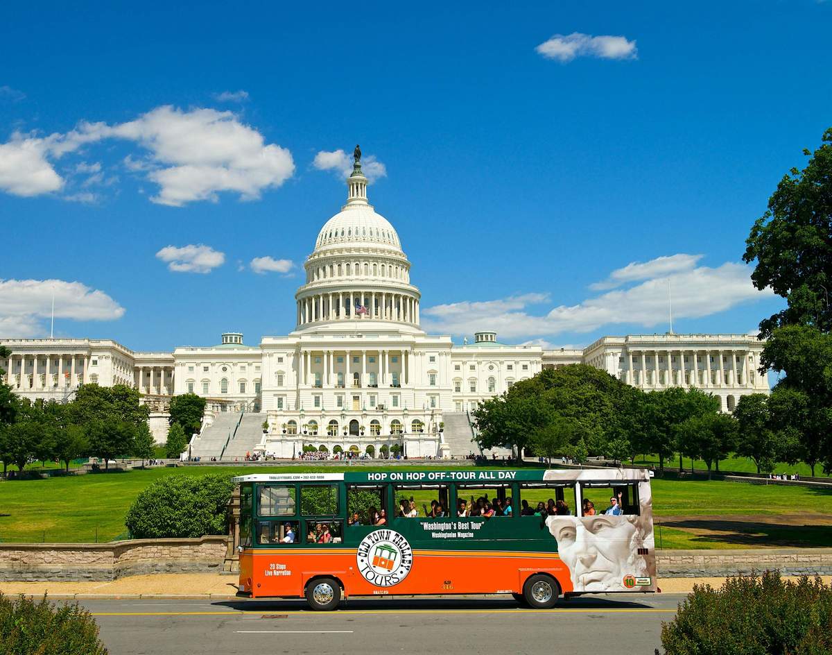 Washington DC : Billet Hop-on Hop-off Old Town Trolley Un bus touristique roule devant le Capitole des États-Unis sous un ciel bleu clair.